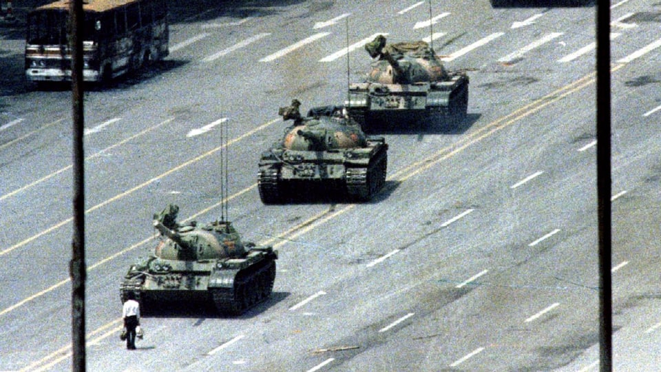 Panzer. Davor steht ein Mensch. Es ist ein historisches Bild von 1989.