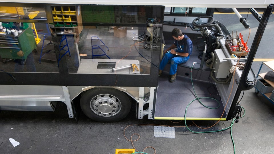 Arbeiter arbeitet an einem halbfertigen Bus