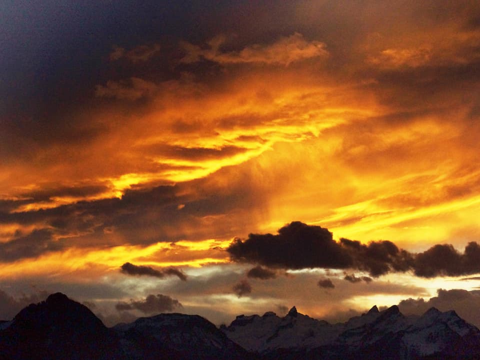 Oranger, gelber, grauer und schwarzer Himmel. Unten im Bild die Zentralschweizer Bergkette.