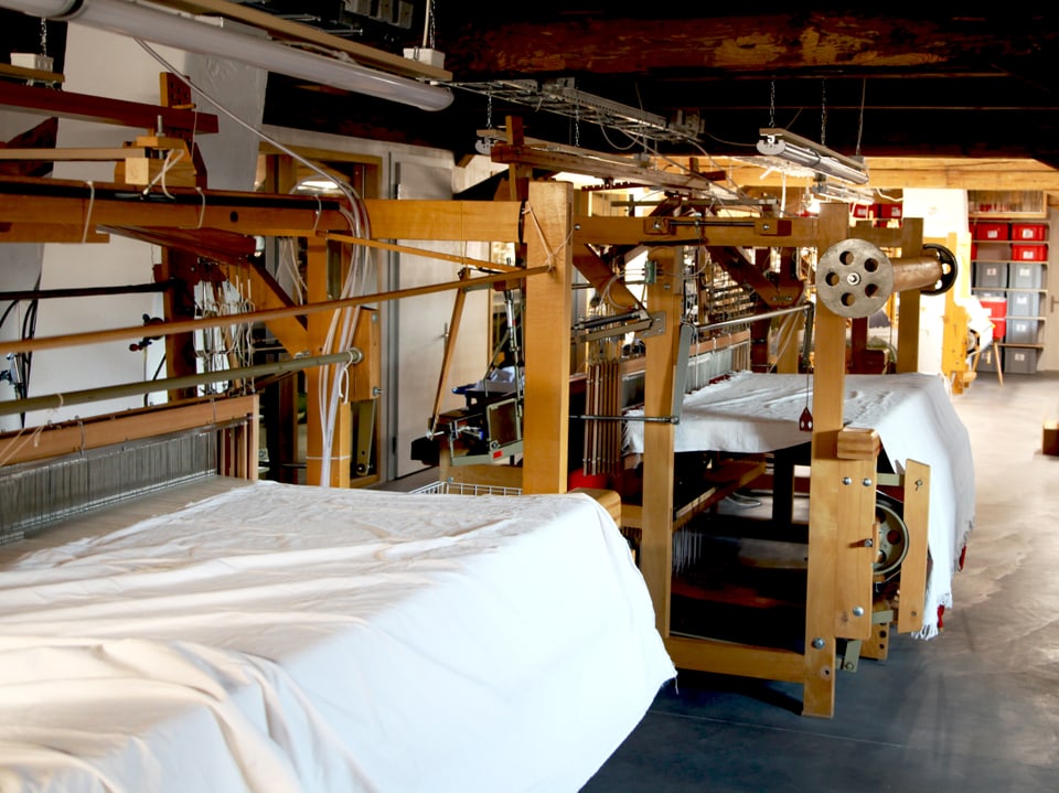 Im Raum des Dackstockes befinden sich zwei grosse Webstühle, auf welchen zurzeit grosse, weisse Stoffe produziert werden.