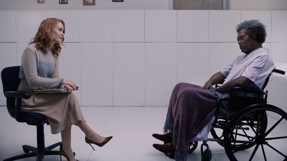 Elijah sitzt im Rollstuhl. Eine Therapeutin redet auf ihn ein.