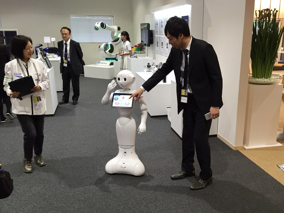Japanischer Mann präsentiert kleinen Roboter. 