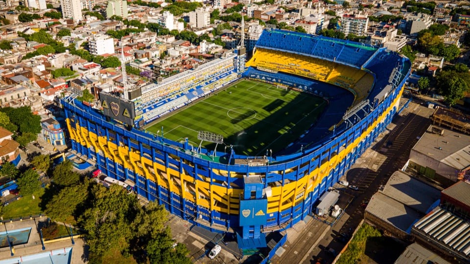 Grosses, gelb-blaues Stadion, eng umgeben von Häusern