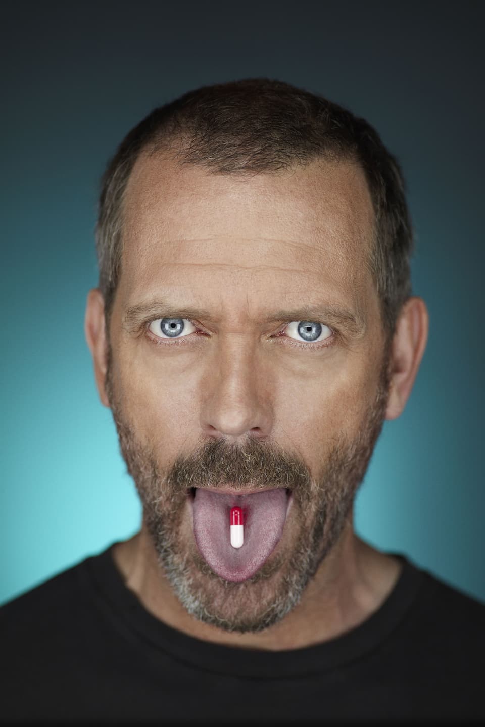 Ein Mann streckt dem Betrachter die Zunge heraus. Auf der Zunge liegt eine Tablette.