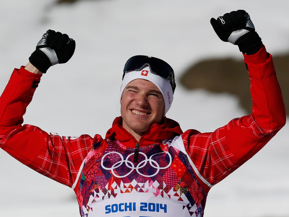Dario Cologna jubelt in roter Jacke an der Flower Ceremony.