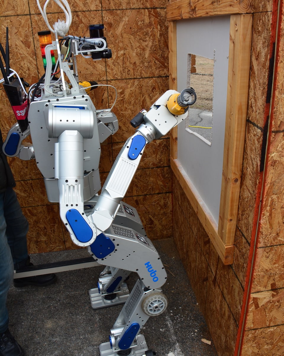 Ein Roboter fräst eine viereckige Öffnung in eine Wand vor ihm.