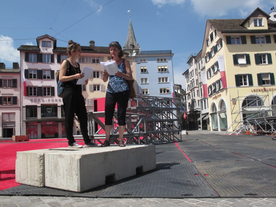 Zwei Frauen auf Betonblock auf Stadtplatz