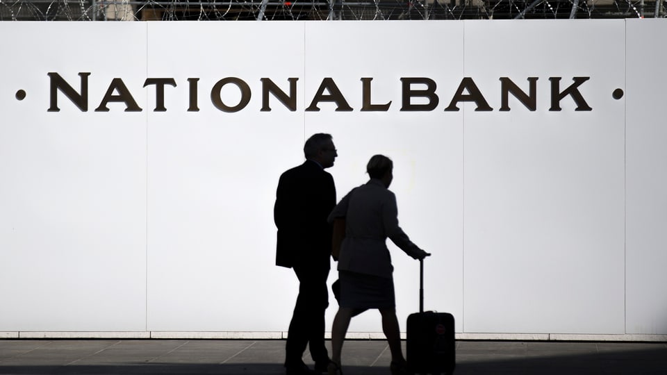 Zwei Personen vor einer Baustellenwand mit der Aufschrift Nationalbank auf dem Berner Bundesplatz