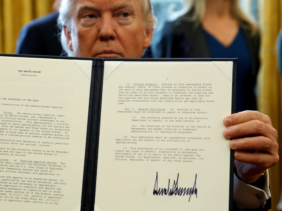 Trump hält unterschriebenes Dekret hoch.