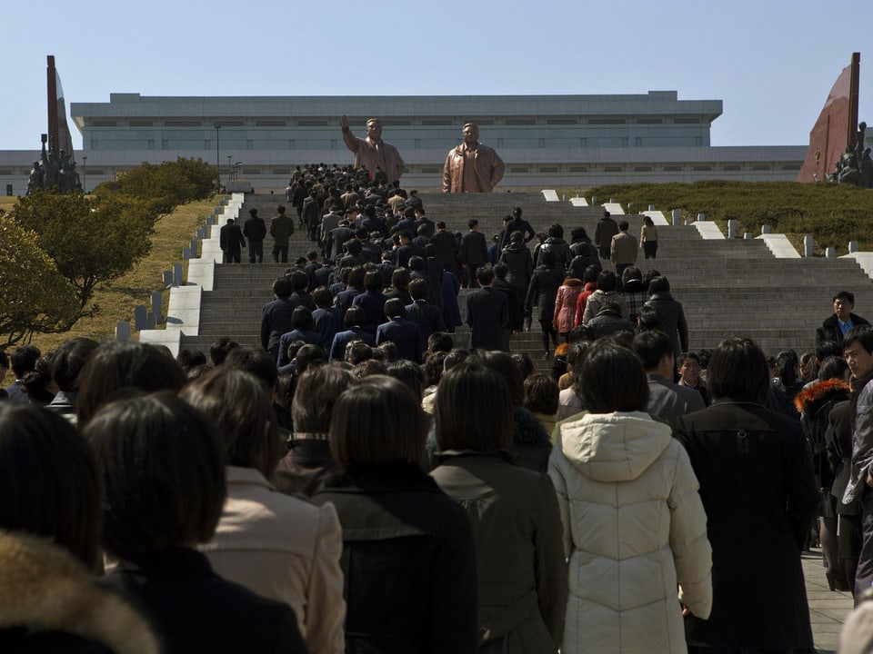 Tausende Menschen stehen an und auf einer Treppe um zum Denkmal für Staatsführer Kim Jong Il und Kim Il Sung.zu gelangen.