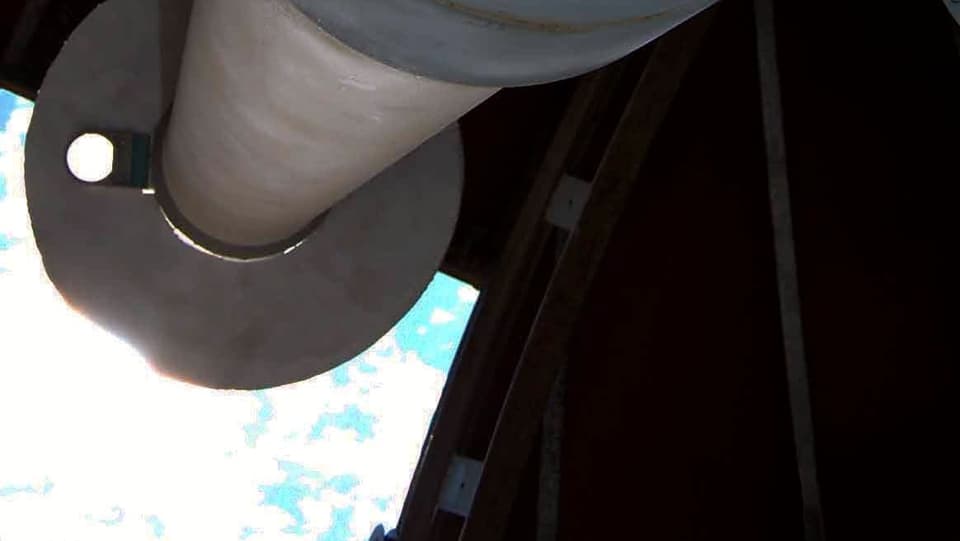 Ein Teleskop das auf eine Dachluke zeigt.