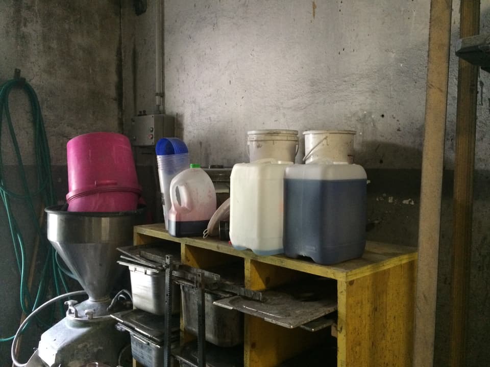 Plastikbehälter auf einem Regal, gefüllt mit farbiger Flüssigkeit. 