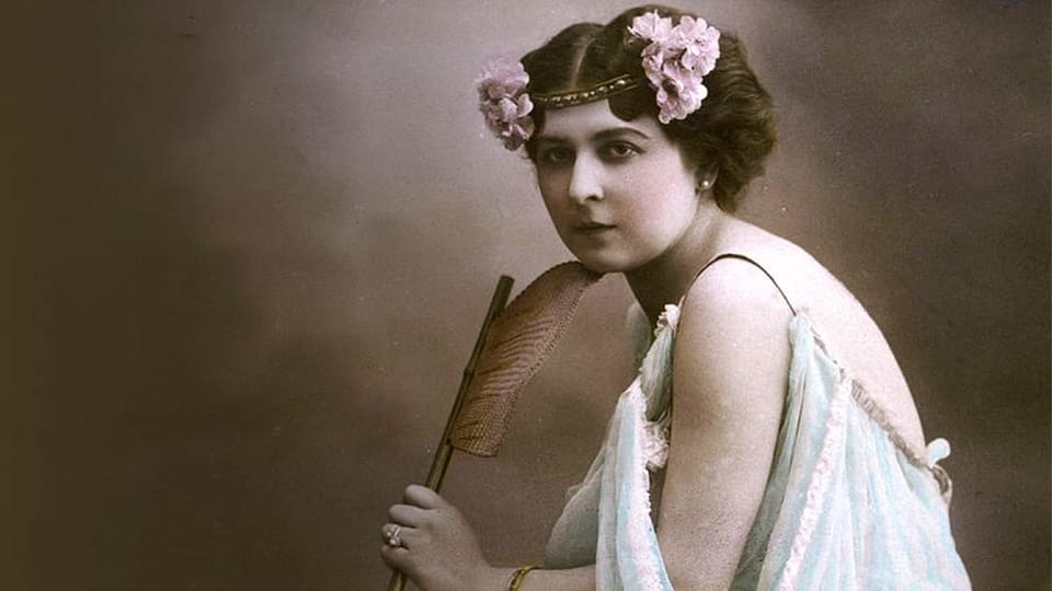 Eine sehr alte Fotografie einer Frau mit Blumen in den Haaren und Fächer.