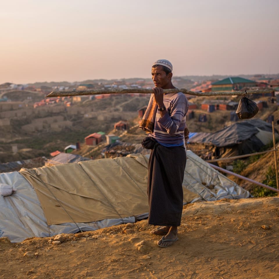 Ein Rohingya hält einen Beutel an einem Stock.