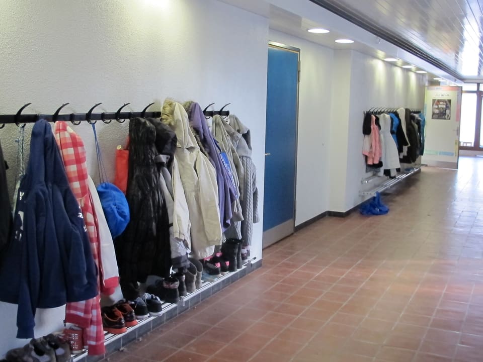 Ein Korridor in einem Schulhaus mit Schülerjacken an der Garderobe.