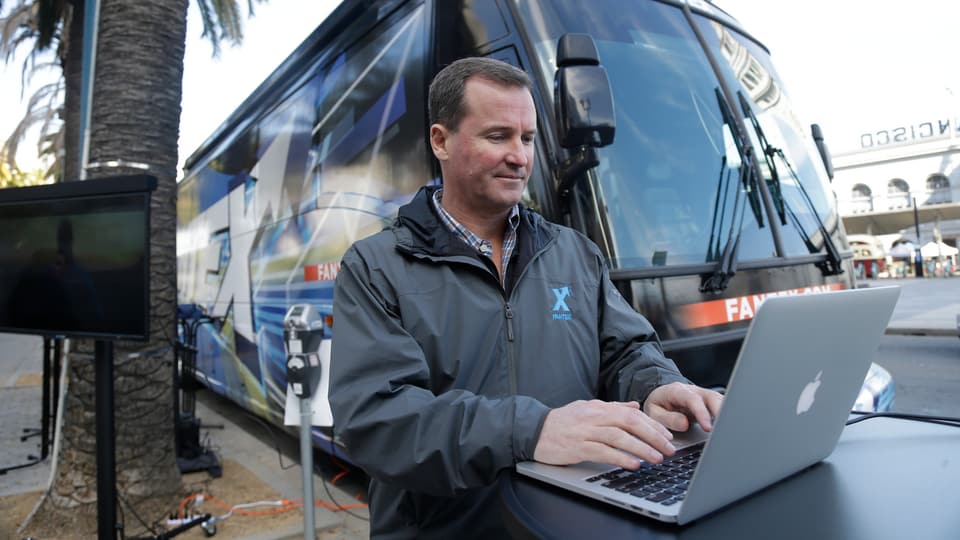 Fantex-CEO Buck French an einem Laptop vor einem Reisecar.