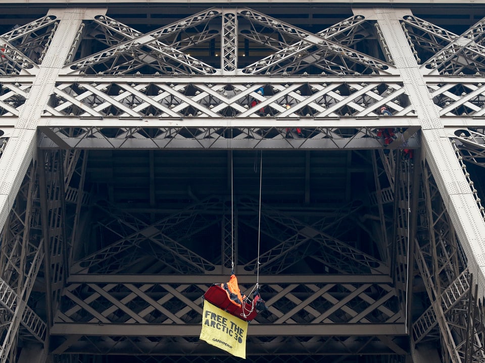 Ein Greenpeace-Aktivist seilt sich mit Plakat am Eiffelturm ab.
