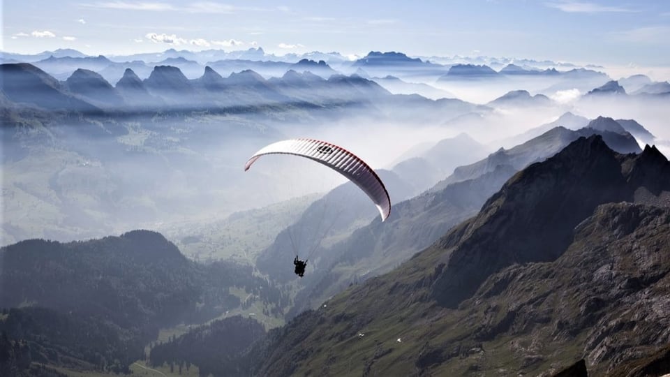 Ein Gleitschirm fliegt über die Ebenalp im Kanton Appenzell Innerhoden mit dem Säntis im Hintergrund.