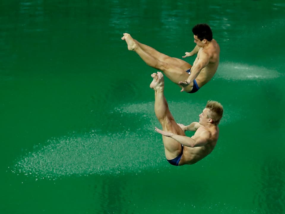 Synchronsprung zweier Athleten in grünes Wasser