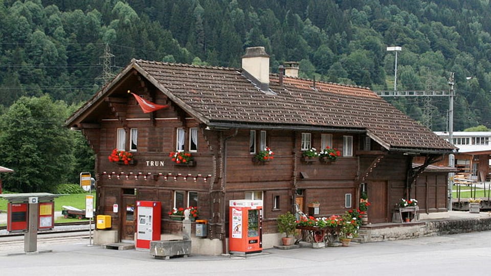 Bahnhof Trun, dunkel gebeizter Holzsbau mit Giebeldach und Geranien