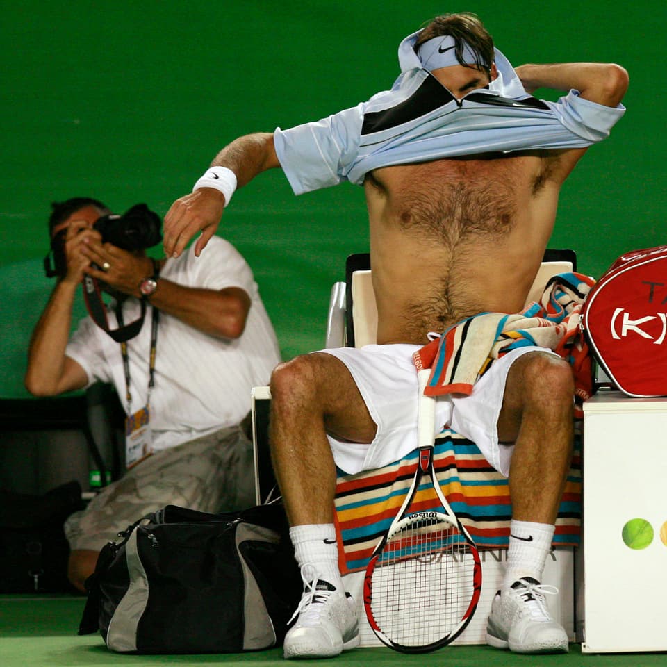 Federer wechselt sein Shirt, er wird von einem Fotografen abgelichtet.