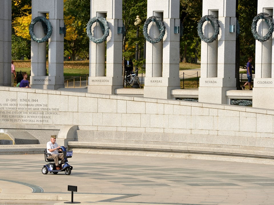 Ein Rollstuhlfaher fährt vor dem Denkmal des zweiten Weltkriegs in Washington vorbei.