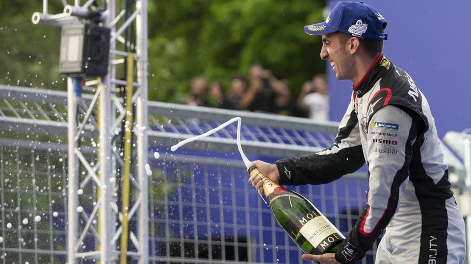 Sebastien Buemi jubelt mit einer Champagner-Flasche.