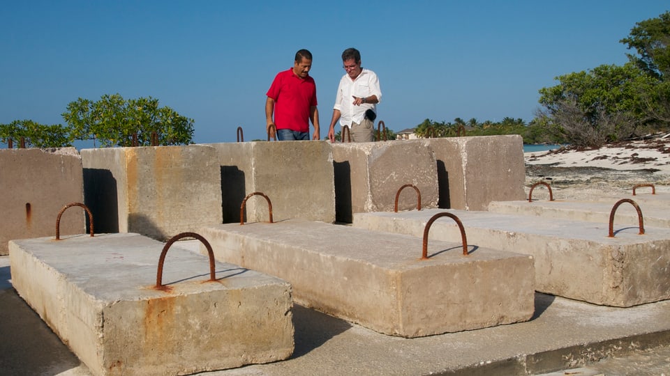 Fernando Martireno und ein Kollege betrachten mehrere Zement-Blöcke an der Küste.