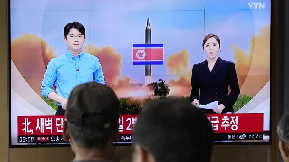 Personen schauen auf TV-Bildschirm, der Nachrichten über nordkoreanische Raketentests zeigt