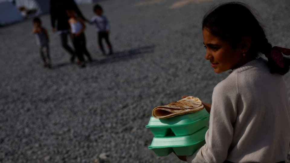 Ein Mädchen trägt warme Mahlzeiten zum Zelt ihrer Familie in Antakya, Türkei am 2. März 2023.