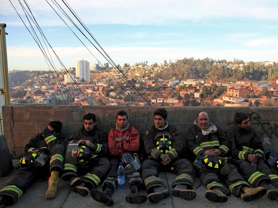 Erschöpfte Feuerwehrmänner sitzen am Boden