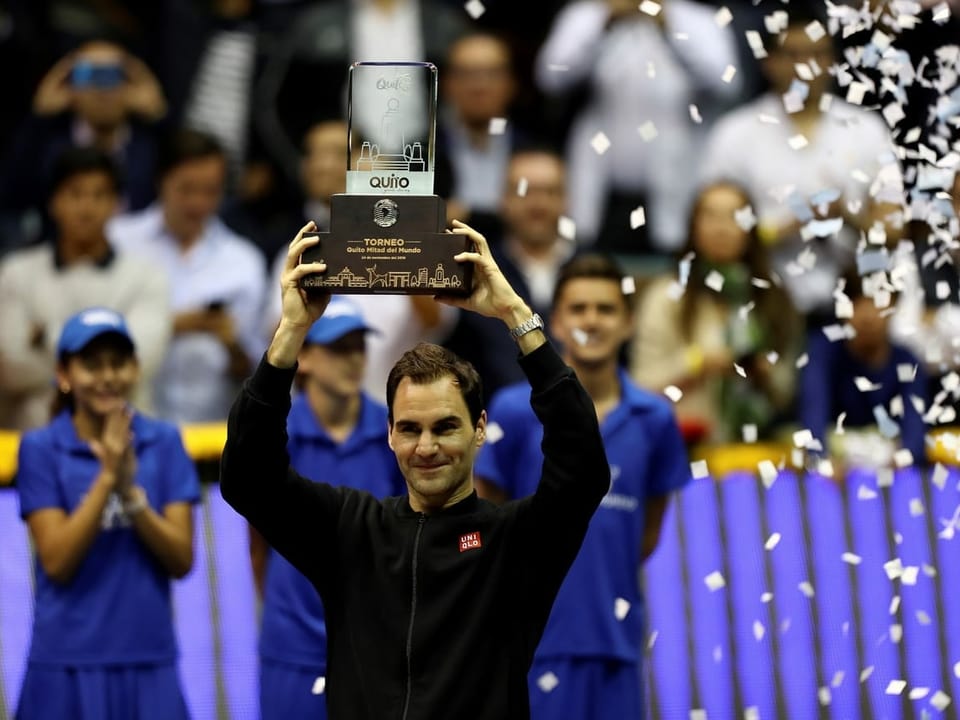 Federer posiert mit einer Trophäe.