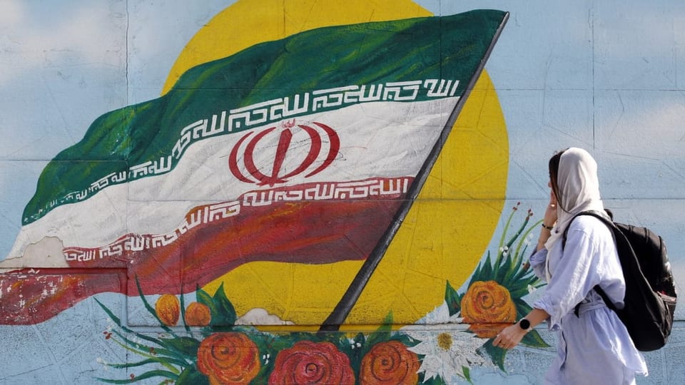 Eine iranische Fahne als Graffiti, eine Frau mit Kopftuch. 