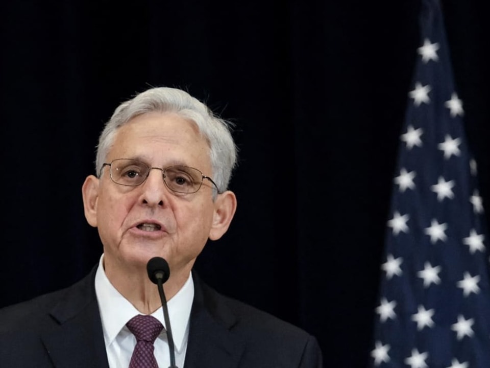 Merrick Garland an einem Mikrofon, dahinter eine US-Flagge