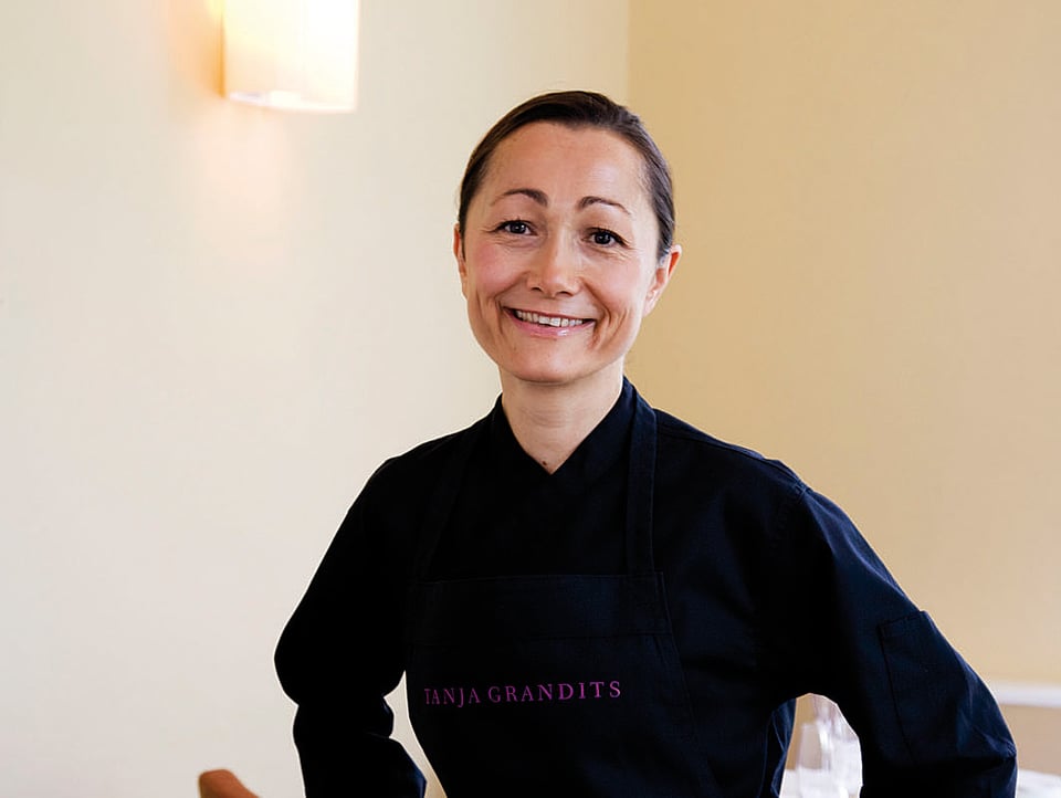 Tanja Grandits posiert in schwarzer Kochuniform im Restaurant.