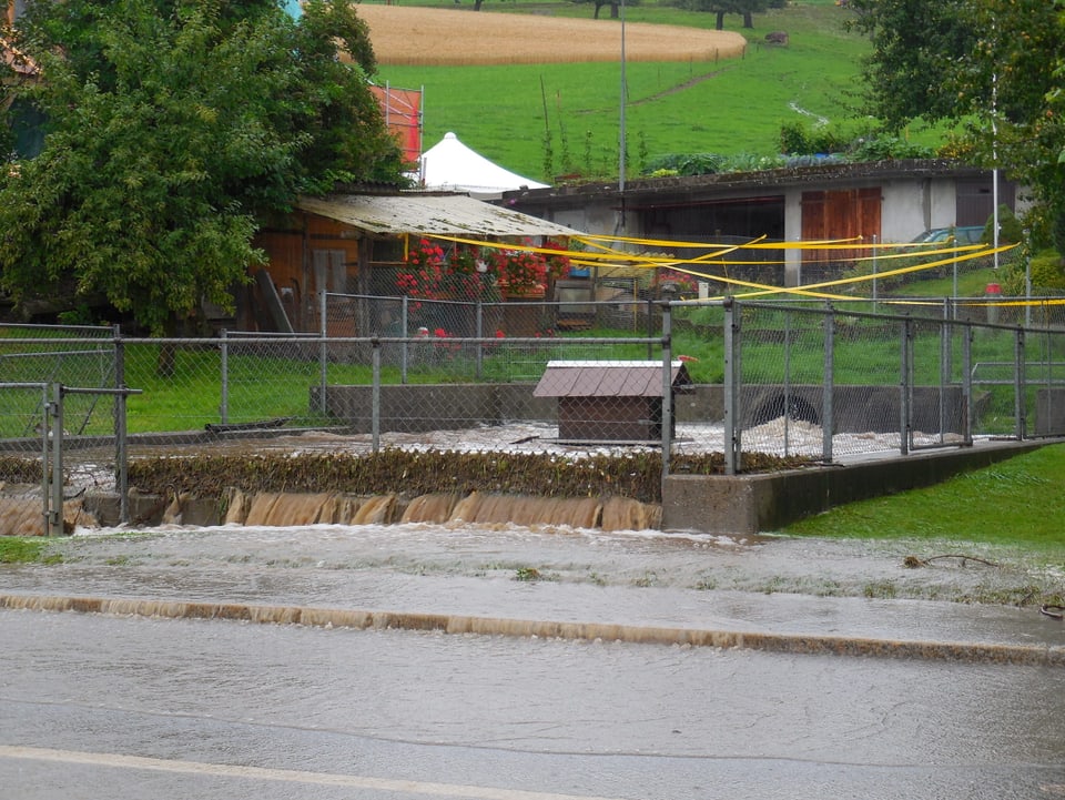 Das Auffangbecken des Dorfbachs in Zäziwil ist voll. Das Wasser fliesst ungehindert über die Strasse.