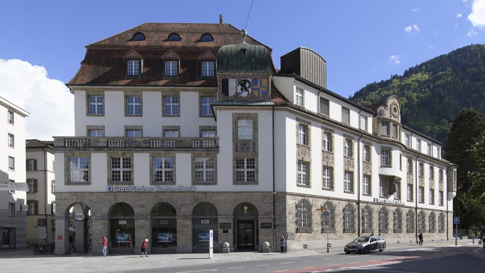 Historisches Rathausgebäude in europäischer Stadt mit Berg im Hintergrund.