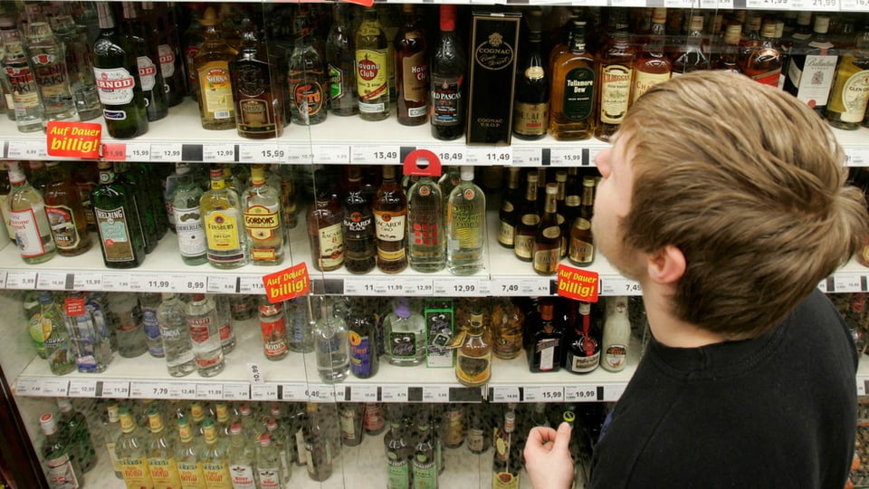 Jugendlicher steht vor einem Verkaufsregal mit Alkohol.