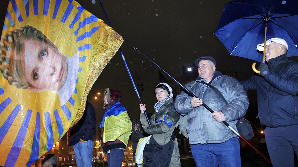 Demonstranten halten eine Fahne mit dem Bild Timoschenkos.