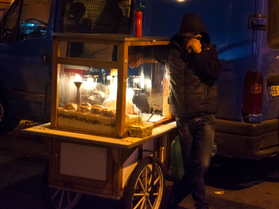 Ein Maisverkäufer neben seinem Stand schützt Mund und Nase vor Tränengas.