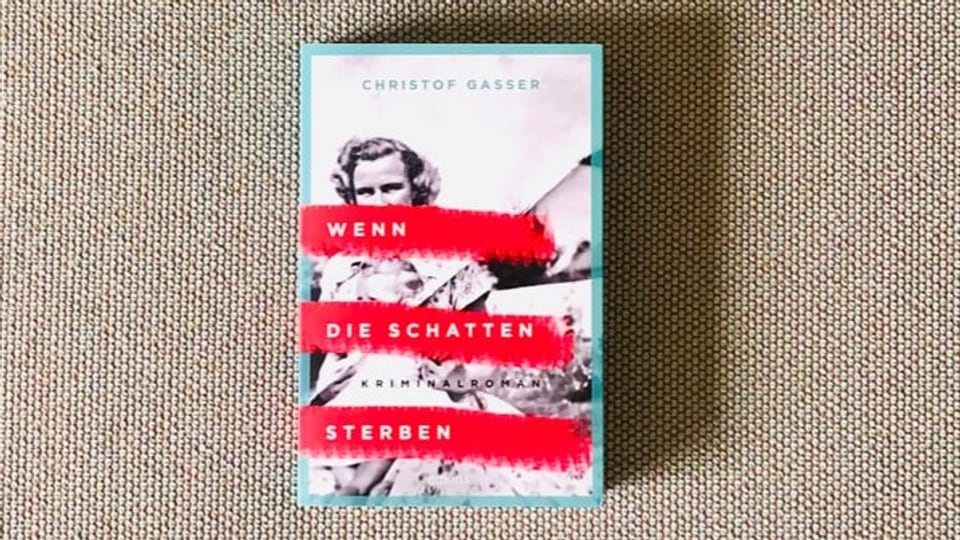 Krimi Nummer 2 «Wen die Schatten sterben» von Christof Gasser liegt auf einem beigen Sofastoff