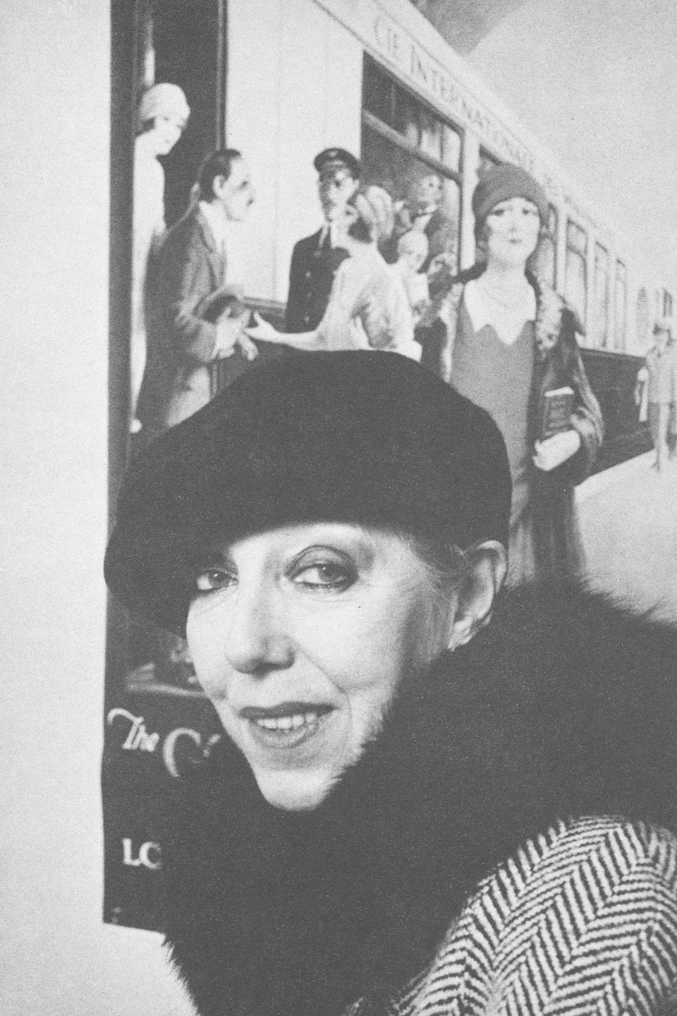 Frau mit Hut vor Bild mit Zug aus den 1920-er Jahren.