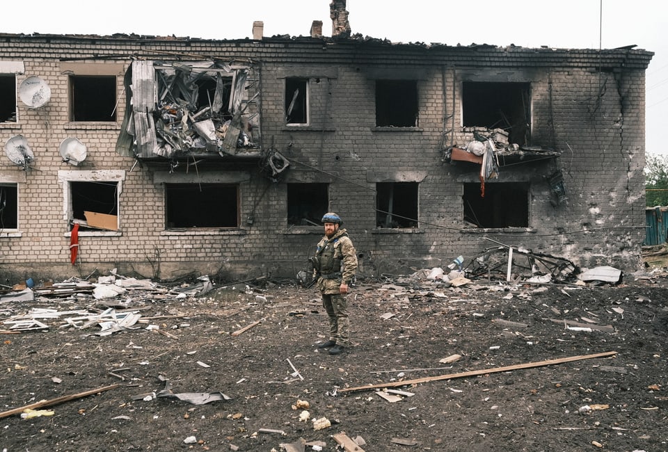Soldat vor zerstörtem Gebäude.