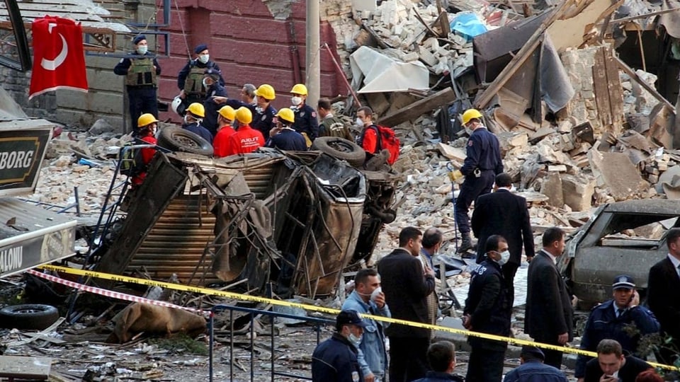 Menschen stehen bei den Trümmern eines Gebäudes nach einem Anschlag.