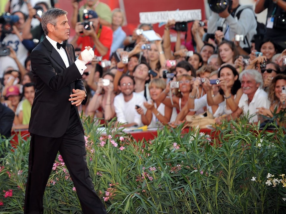 Schauspieler George Clooney im Vordergrund, Schaulustige im Hintergrund