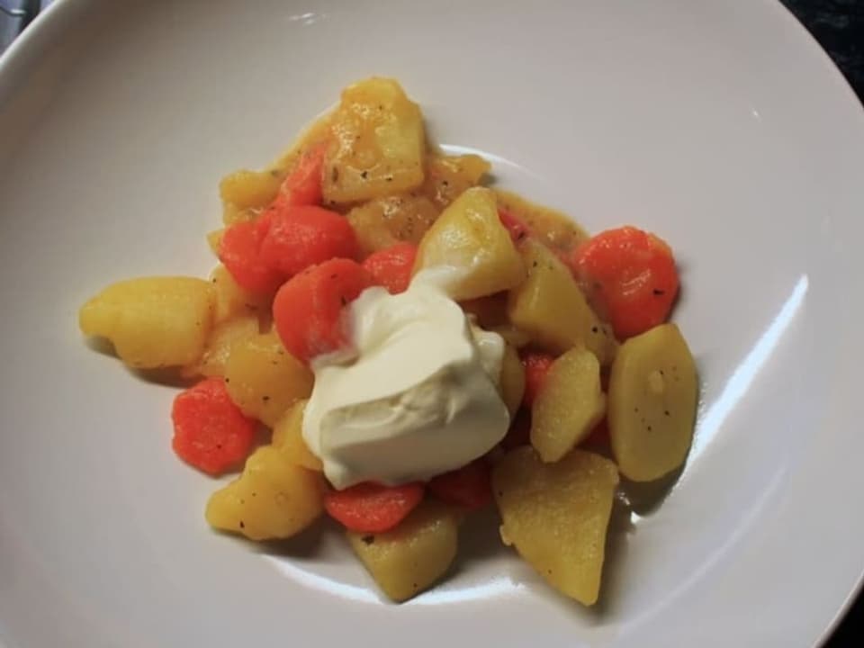 Ein Teller mit Kartoffeln-Rüebli-Eintopf und Crème fraîche.