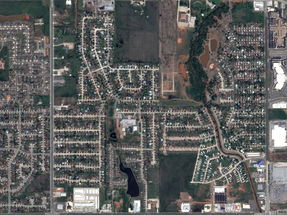 Satellitenbild der intakten Siedlung, im Zentrum ein grosses Schulgebäude.