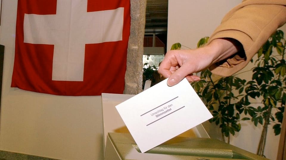 Ein Wahlcouvert, das in die Urne geworfen wird, dahinter die Schweizer Fahne. 