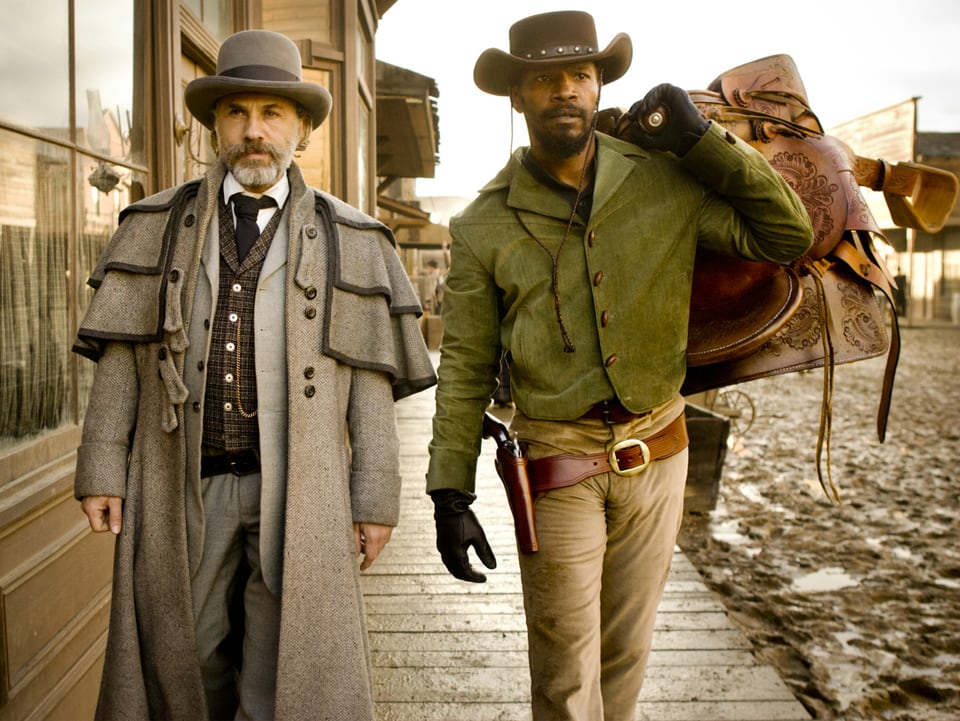 Kopfgeldjäger Dr. King Schultz und der Sklave Django (Jamie Foxx) laufen durch eine Strasse im Wilden Westen. 