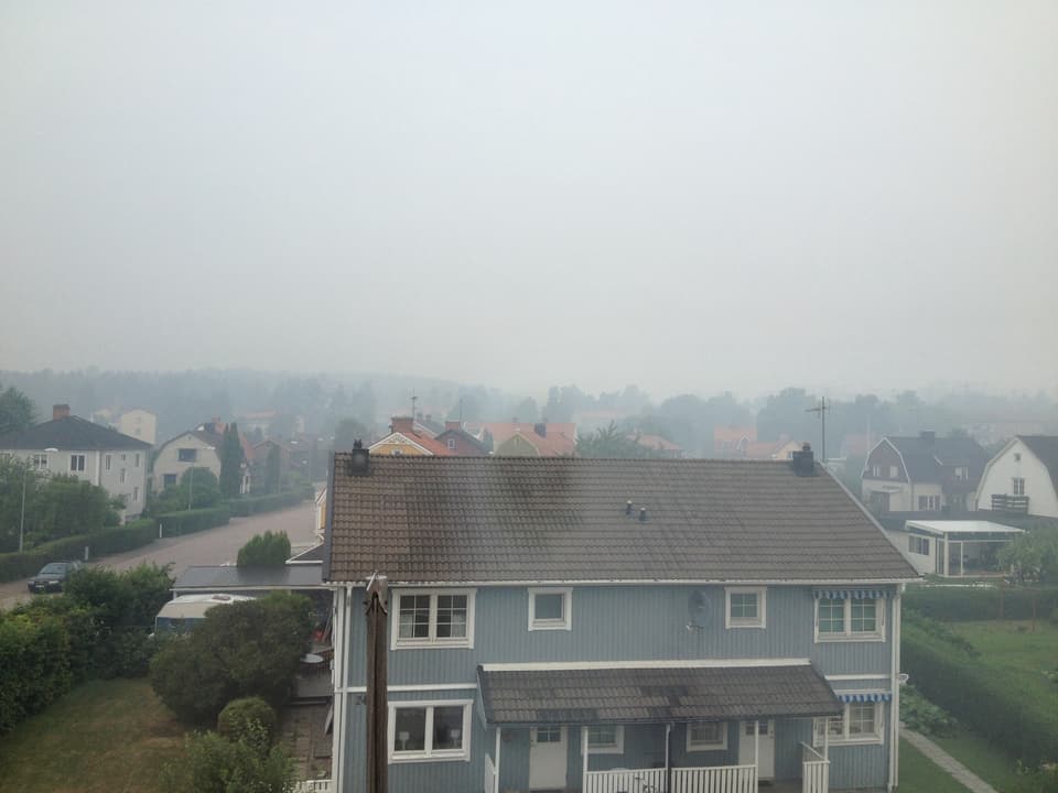 Blick auf Häuser, über denen eine Rauchwolke hängt.